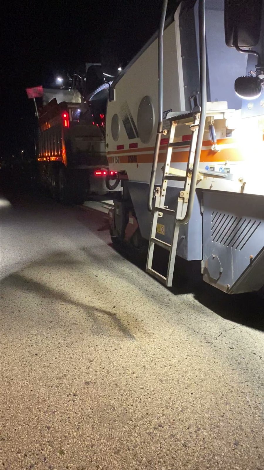 Milling machine loading a dump truck during night operations on IH-94